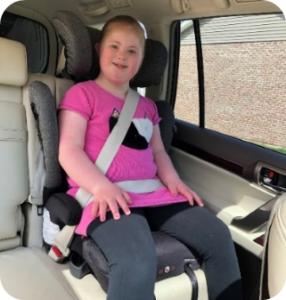 Child with Down Syndrome riding in a booster seat in a passenger vehicle