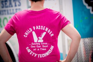 Here, a Child Passenger Safety Technician proudly shows off her T-shirt at a checkup event.